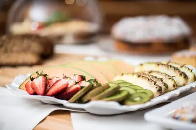 a table with a plate of fruit and vegetables at Hotel Vernel in Santa Cristina in Val Gardena