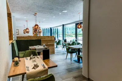 a restaurant with tables and chairs and windows at Hotel Vernel in Santa Cristina in Val Gardena
