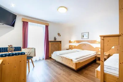 a bedroom with two beds and a tv in it at Hotel Vernel in Santa Cristina in Val Gardena