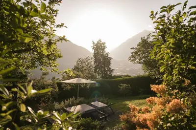 a garden with a table and an umbrella at Boutiquehotel Minigolf in Tirolo