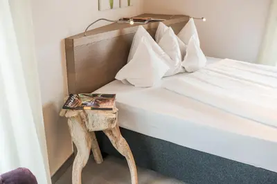 a bed with a side table with a book on it at Boutiquehotel Minigolf in Tirolo