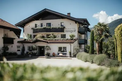a large white building with a courtyard and palm trees at Boutiquehotel Minigolf in Tirolo