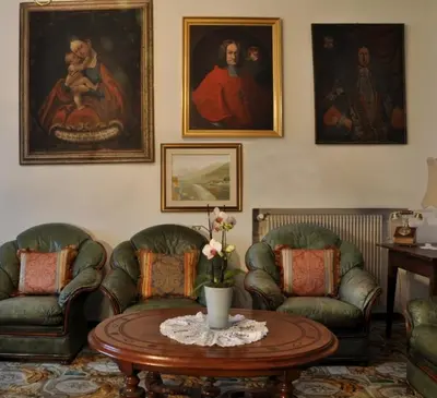 a living room with two chairs and a table and paintings at Hotel Ansitz Kandelburg in Mühlbach