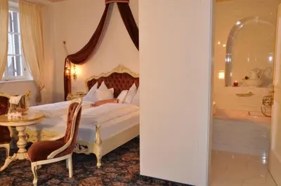 a bedroom with a bed and a tub and a table at Hotel Ansitz Kandelburg in Mühlbach