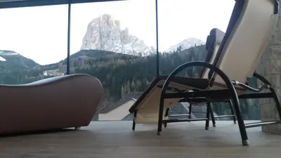 a chair in a room with a view of a mountain at Hotel Garnì Gardena - Appartments in Santa Cristina in Val Gardena