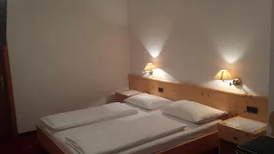 a bedroom with two beds and two lights on the wall at Hotel Garnì Gardena - Appartments in Santa Cristina in Val Gardena