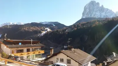 a view of a mountain with a house and a building at Hotel Garnì Gardena - Appartments in Santa Cristina in Val Gardena