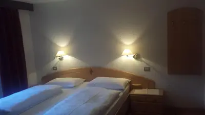 two beds in a bedroom with two lights on the wall at Hotel Garnì Gardena - Appartments in Santa Cristina in Val Gardena