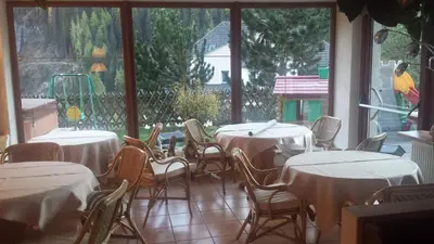 a dining room with tables and chairs and a large window at Hotel Garnì Gardena - Appartments in Santa Cristina in Val Gardena