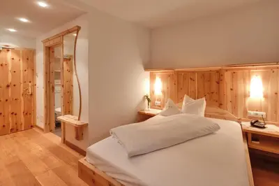 a bedroom with a large white bed and a bathroom at Hotel Jonathan in Naz-Sciaves