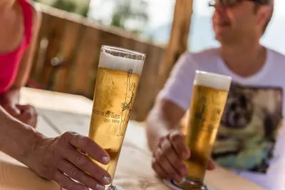 two people sitting at a table with two glasses of beer at Hotel Jonathan in Naz-Sciaves