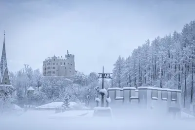 a person standing in the snow in front of a building at Hotel Reipertingerhof in Brunico