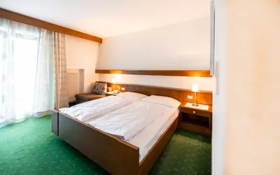 a bedroom with a large bed and a window at Hotel Reipertingerhof in Brunico
