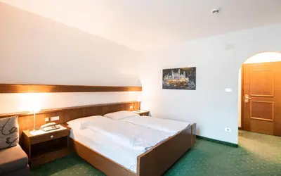 a hotel room with a bed and a couch at Hotel Reipertingerhof in Brunico