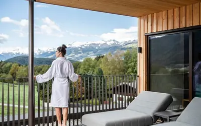a woman standing on a balcony looking out at the mountains at Hotel Olympia in Brunico