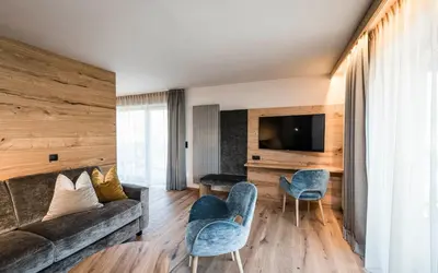 a living room with a couch and chairs and a tv at Hotel Olympia in Brunico