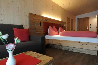 a bedroom with a large bed with red pillows at Naturhotel Haller in Racines
