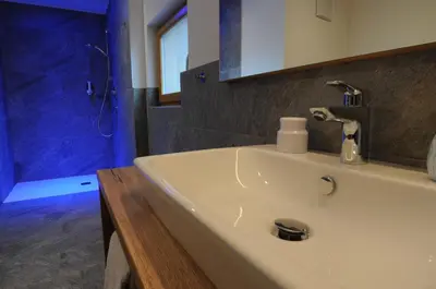 a bathroom with a white sink and a shower at Naturhotel Haller in Racines