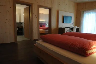 a bedroom with two red beds and a room with a bedroomictericterictericter at Naturhotel Haller in Racines