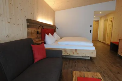 a bedroom with a bed and a couch in a room at Naturhotel Haller in Racines
