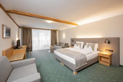 a hotel room with a bed and a couch at Wirtshaushotel Alpenrose in San Lorenzo di Sebato