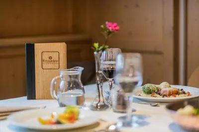 a table with plates of food and glasses of wine at Wirtshaushotel Alpenrose in San Lorenzo di Sebato