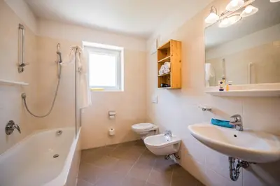 a bathroom with a sink and a tub and a toilet at Wirtshaushotel Alpenrose in San Lorenzo di Sebato