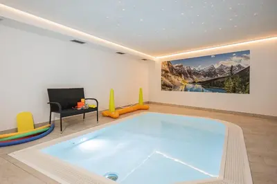 a swimming pool in a room with a painting on the wall at Wirtshaushotel Alpenrose in San Lorenzo di Sebato