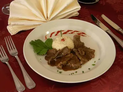 a plate of food with meat and rice on a table at Hotel Bologna in Brunico