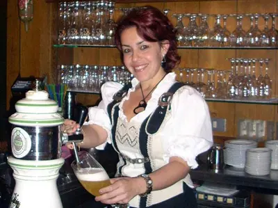 a woman in a bar holding a glass of beer at Hotel Bologna in Brunico