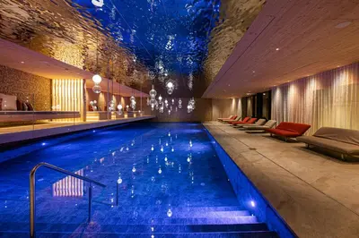 a large swimming pool in a hotel with blue water at Hotel Anewandter in Brunico