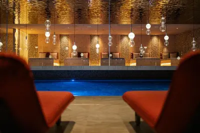 a hotel lobby with a swimming pool and chairs at Hotel Anewandter in Brunico