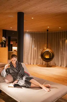 a woman sitting on a bed in a room at Hotel Anewandter in Brunico