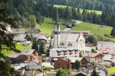 a small town with a church in the mountains at Hotel Cavallino in Badia