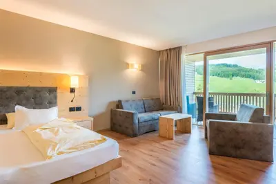a hotel room with a bed and a living room at Hotel Cavallino in Badia