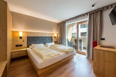 a bedroom with a large bed and a large window at Hotel Cavallino in Badia