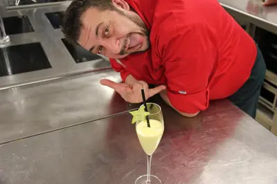 a man in a red shirt manipulating a drink at Hotel Cavallino in Badia