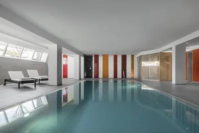 a swimming pool in a building with a lobby at Hotel Krondlhof in Brunico