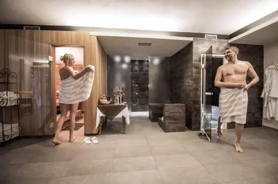 a man and a woman standing in a bathroom at Hotel Krondlhof in Brunico