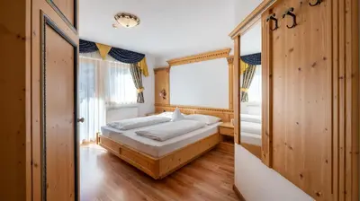 a bedroom with a bed and a window at Garni Hotel and Apartments Wildbach in Selva di Val Gardena