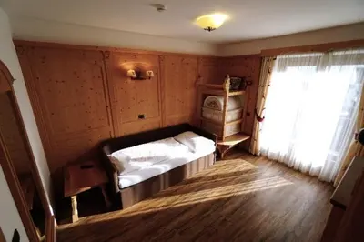 a bedroom with a bed in a room with a window at Garni Hotel and Apartments Wildbach in Selva di Val Gardena