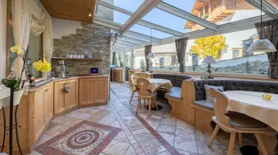 a conservatory with a table and chairs in a restaurant at Garni Hotel and Apartments Wildbach in Selva di Val Gardena
