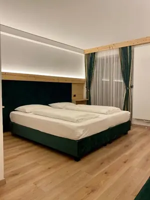 a large bed in a room with a wooden floor at Garni Hotel and Apartments Wildbach in Selva di Val Gardena