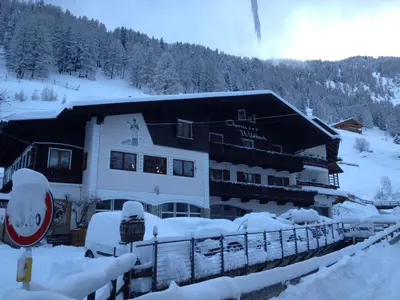 a building covered in snow in front of a mountain at Garni Hotel and Apartments Wildbach in Selva di Val Gardena