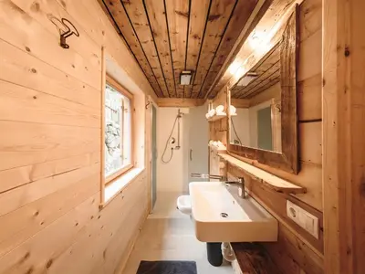 a bathroom with wooden walls and a sink and a mirror at Hirschhof Pfrein - Hideaway in Chiusa