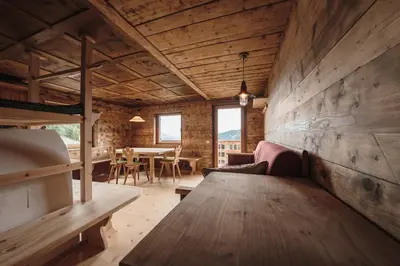 a room with a wooden wall with a bench and a table at Hirschhof Pfrein - Hideaway in Chiusa