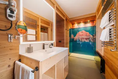 a bathroom with a sink and a large painting on the wall at Hotel Villa Alpina ***S in Cortina dʼAmpezzo