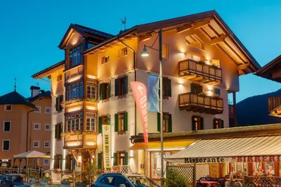 a building with cars parked in front of it at Hotel Villa Alpina ***S in Cortina dʼAmpezzo