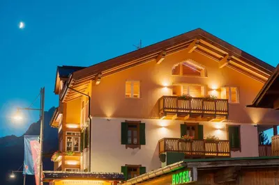 a white building with windows and balconies at night at Hotel Villa Alpina ***S in Cortina dʼAmpezzo