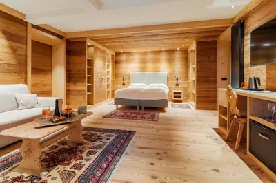 a bedroom with a bed in a room with wooden walls at Hotel Villa Alpina ***S in Cortina dʼAmpezzo